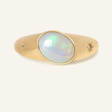 Supernova Signet Opal Ring in yellow gold, resting on a warm linen background