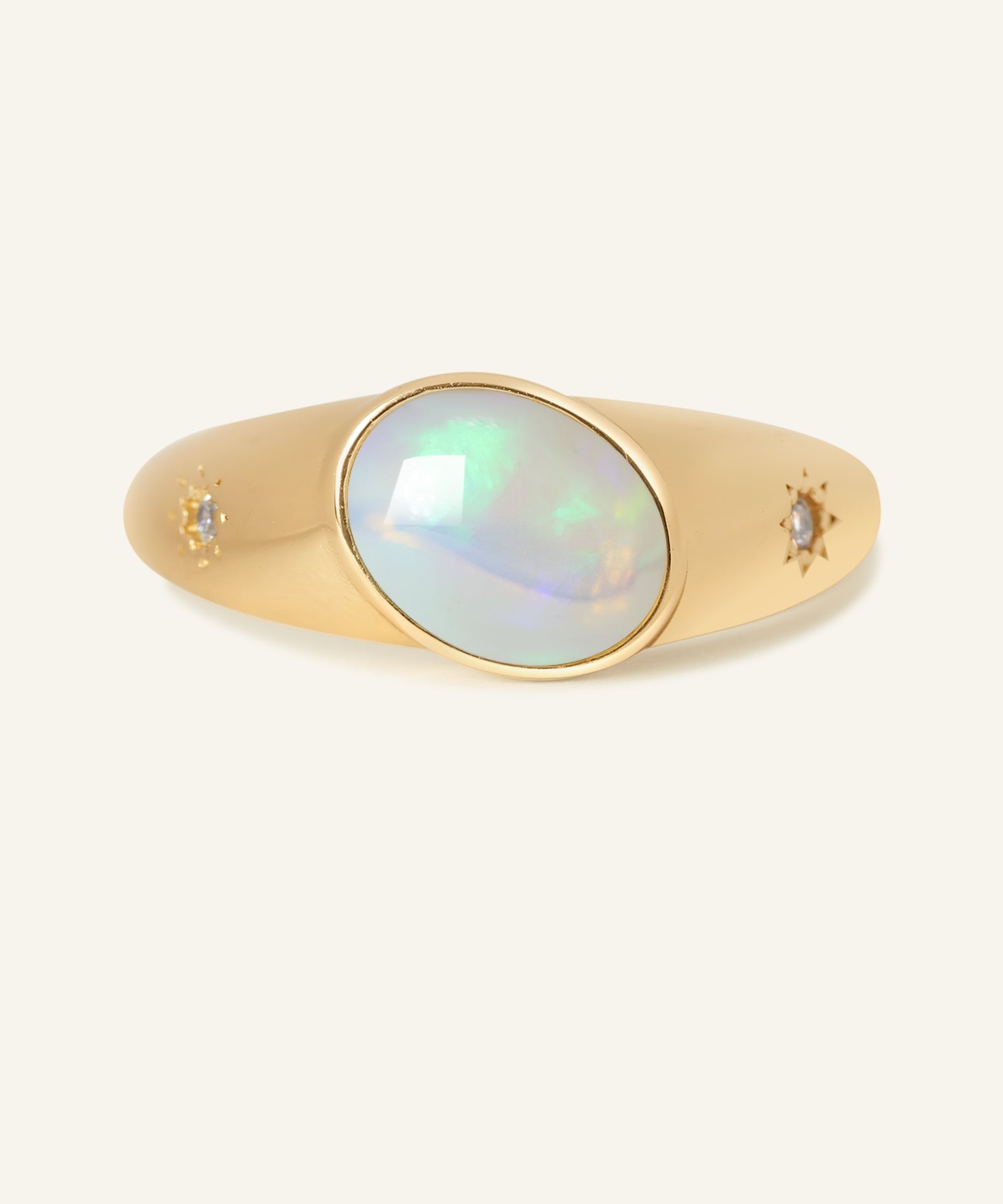 Supernova Signet Opal Ring in yellow gold, resting on a warm linen background