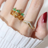 A model wearing a trio of pineapple-themed rings featuring yellow citrine gemstones mimicking the fruit's body, with green cubic zirconia leaves at the top, all set in a yellow gold band.