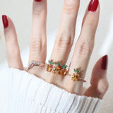 A model wearing a trio of pineapple-themed rings featuring yellow citrine gemstones mimicking the fruit's body, with green cubic zirconia leaves at the top, all set in a rose gold band.