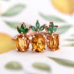 A trio of pineapple-themed rings featuring yellow citrine gemstones mimicking the fruit's body, with green cubic zirconia leaves at the top, all set in a rose gold band.