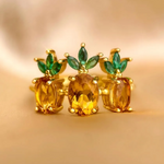 A trio of pineapple-themed rings featuring yellow citrine gemstones mimicking the fruit's body, with green cubic zirconia leaves at the top, all set in a yellow gold band.