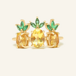 A trio of pineapple-themed rings featuring yellow citrine gemstones mimicking the fruit's body, with green cubic zirconia leaves at the top, all set in a yellow gold band.