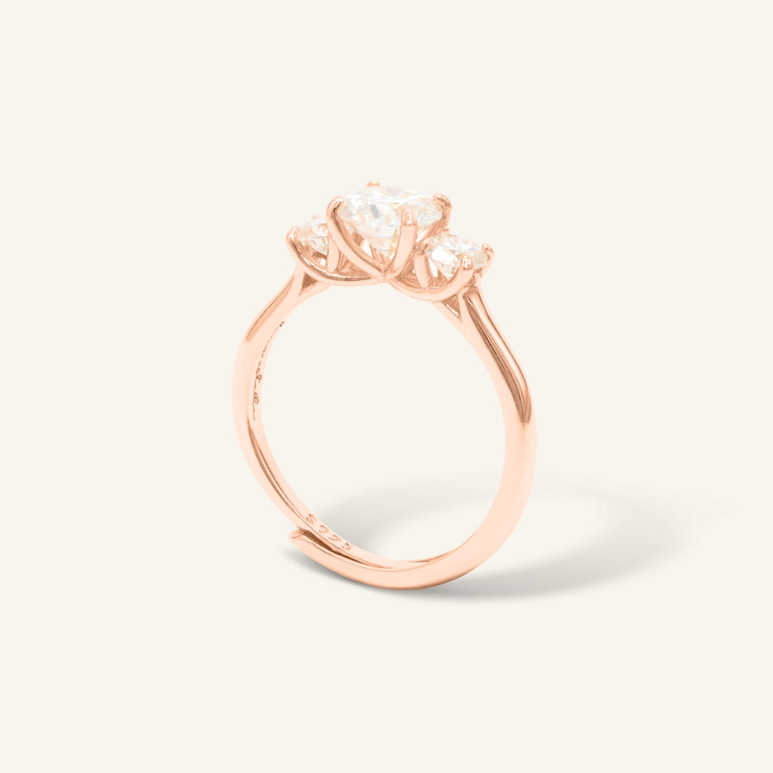 Trilogy Moissanite Ring | Elate in rose gold, resting on a warm linen background