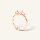 Trilogy Moissanite Ring | Elate in rose gold, resting on a warm linen background