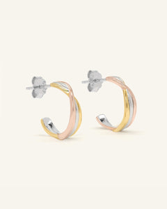 Trinity Twist Studs, resting on a warm linen background