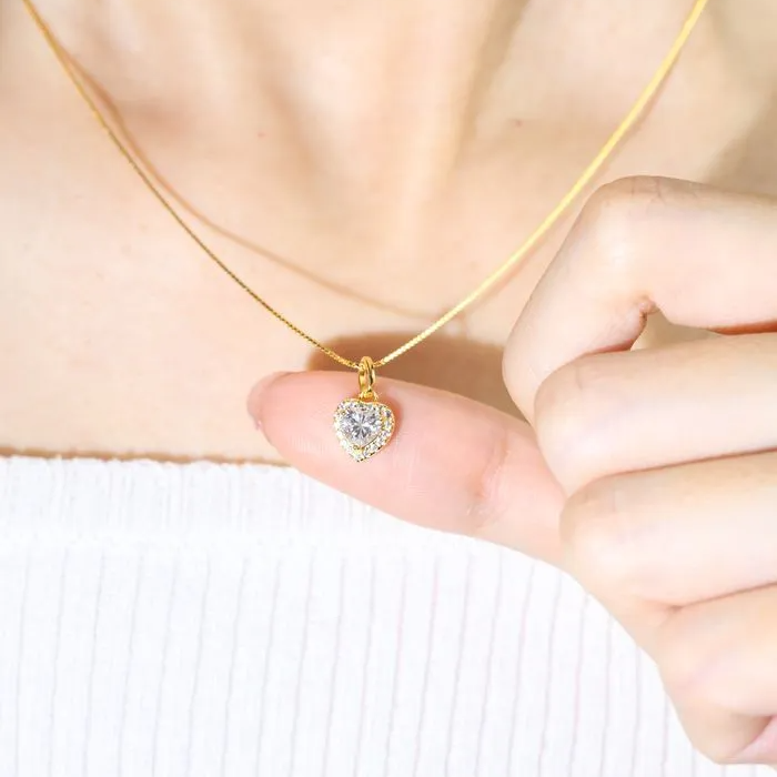 A model wearing the white heart-shaped moissanite halo necklace in yellow gold vermeil, featuring a sparkling moissanite centerpiece surrounded by a halo of cubic zirconias, set on a fine yellow gold vermeil chain.