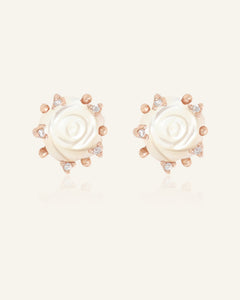 Close-up of the Handcarved White Shell Rose Studs in rose gold, resting on a warm linen background