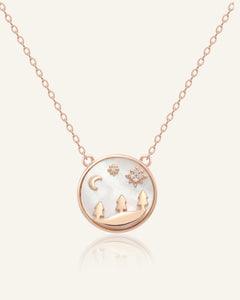 Close-up of the Winterscape Necklace in rose gold, resting on a warm linen background