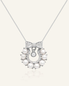 Wreath Ribbon Necklace | Freshwater Pearl in silver, resting on a warm linen background