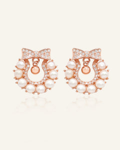 Wreath Ribbon Studs | Freshwater Pearl in rose gold, resting on a warm linen background