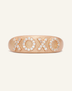 Close-up of the XOXO Ring in rose gold, resting on a warm linen background