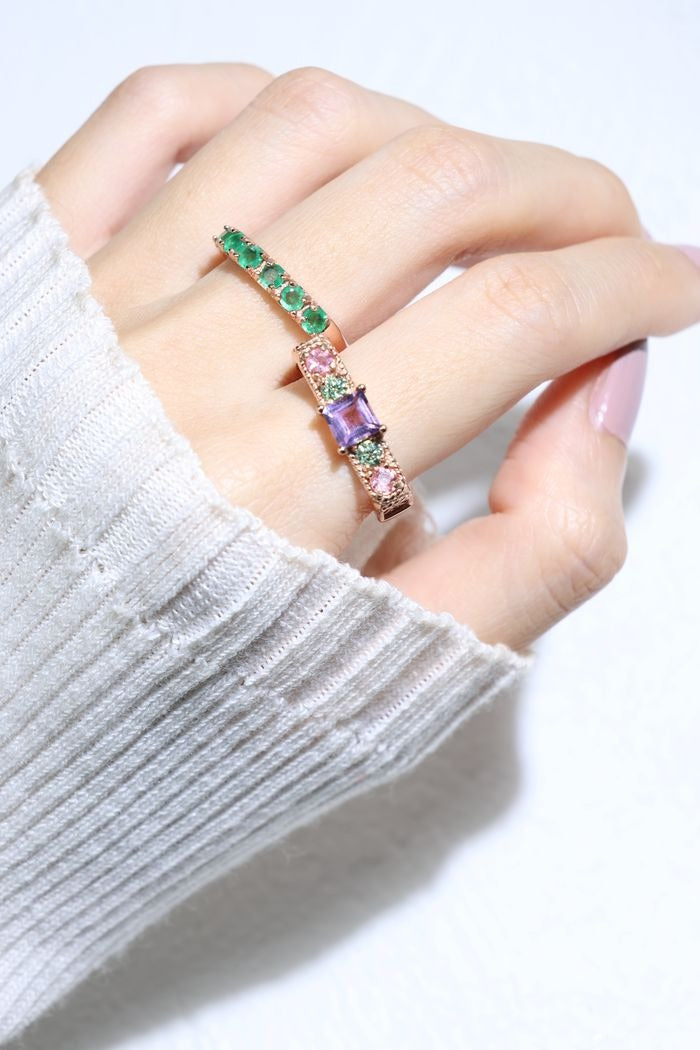 Arc de Triomphe Amethyst Ring in rose gold, close-up worn beside a green gemstone band with an ivory sleeve