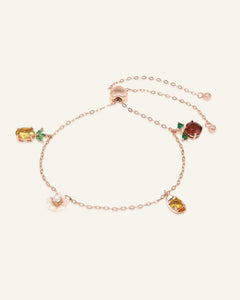 Close-up of the Blessings Charm Slider Bracelet in rose gold, resting on a warm linen background