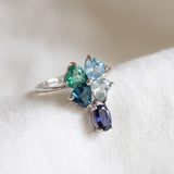 Silver blue topaz clover ring with dangling violet iolite resting on ivory linen