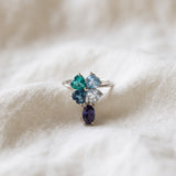 Silver blue topaz clover ring with dangling violet iolite resting on ivory linen