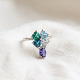Silver blue topaz clover ring with dangling violet iolite resting on ivory linen
