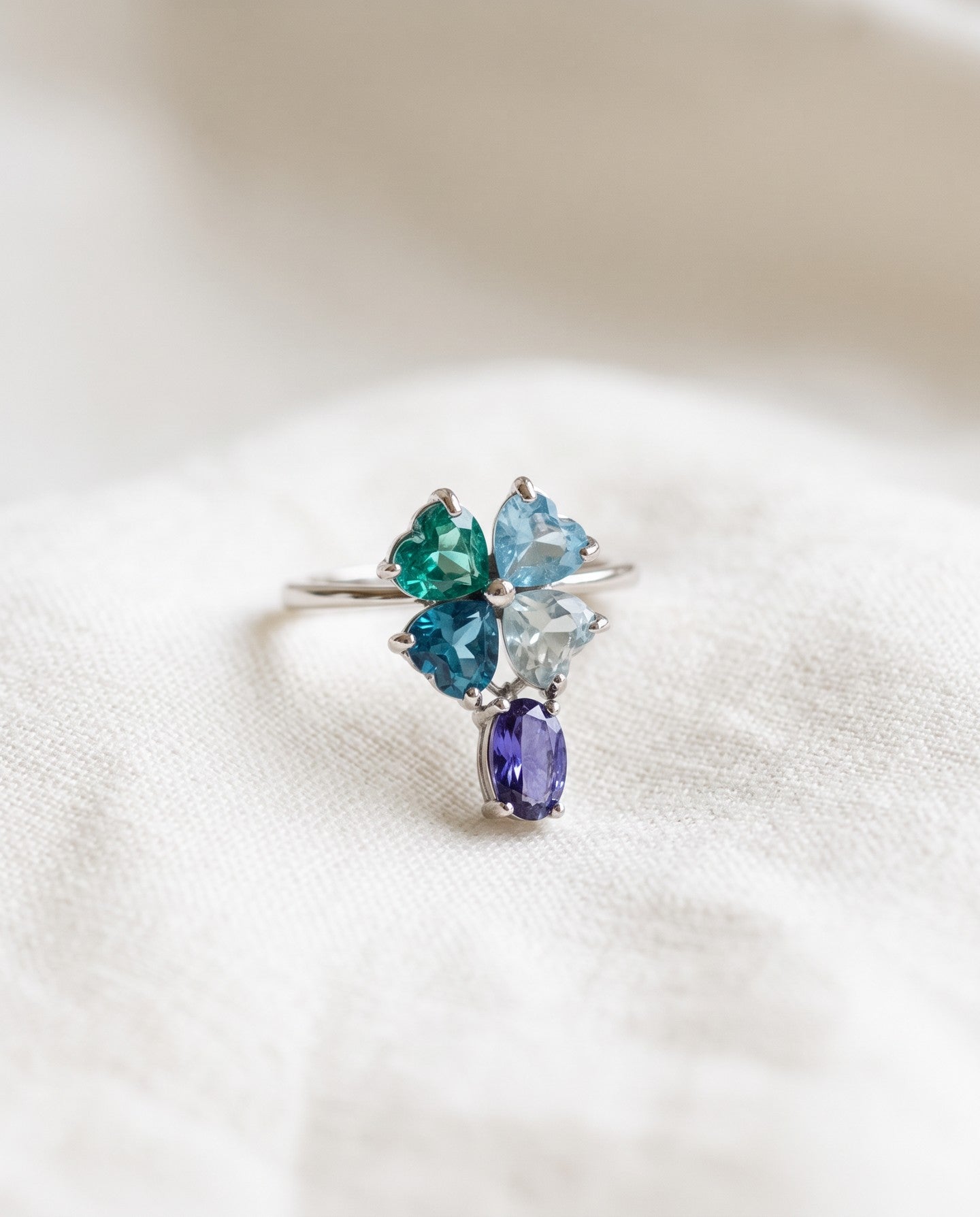 Silver blue topaz clover ring with dangling violet iolite resting on ivory linen