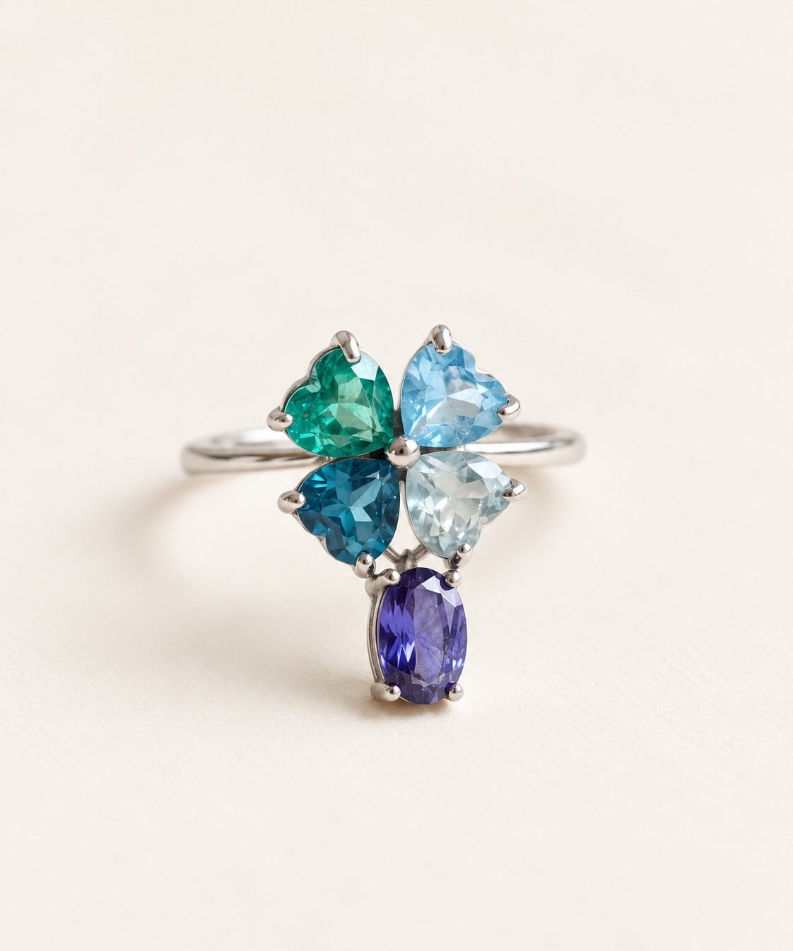 Silver blue topaz clover ring with dangling violet iolite on an ivory background