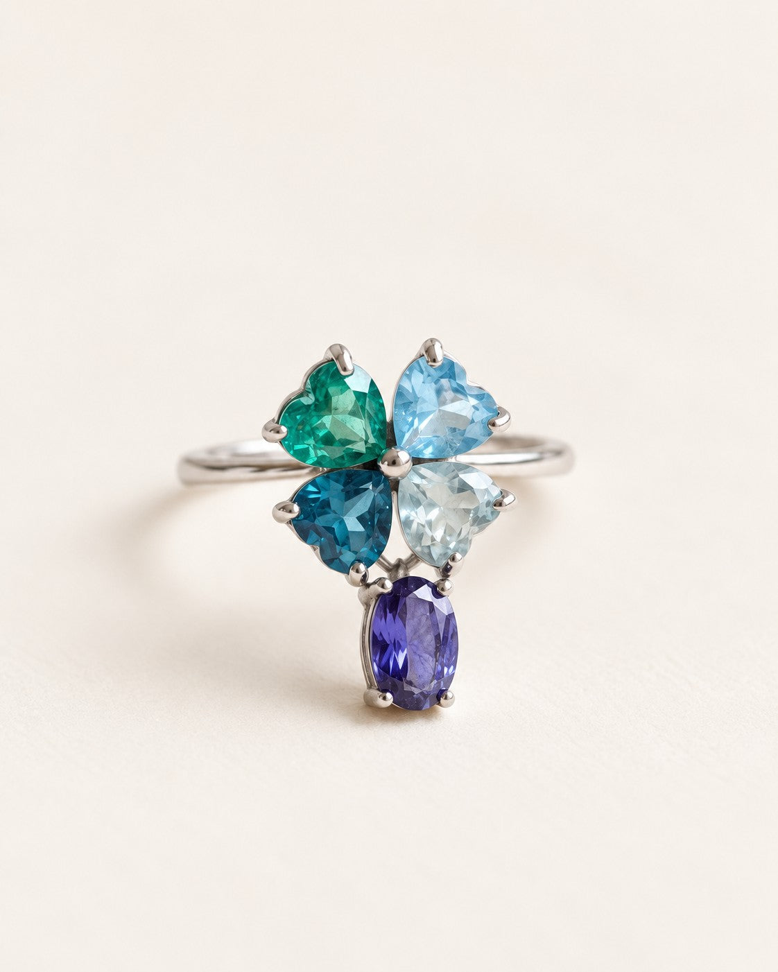 Silver blue topaz clover ring with dangling violet iolite on an ivory background