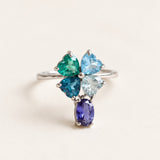 Silver blue topaz clover ring with dangling violet iolite on an ivory background