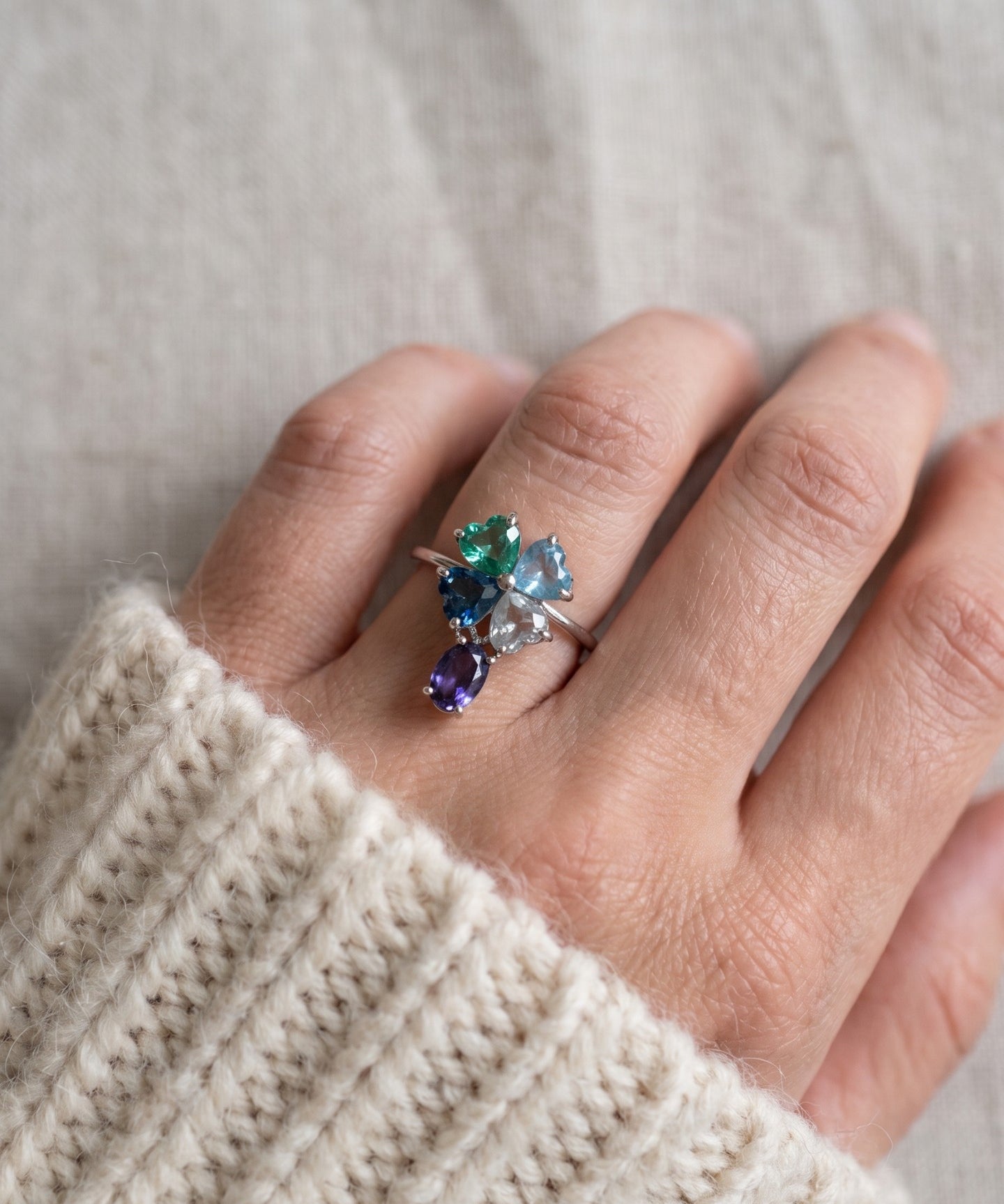 Silver blue topaz clover ring with dangling violet iolite worn on a hand