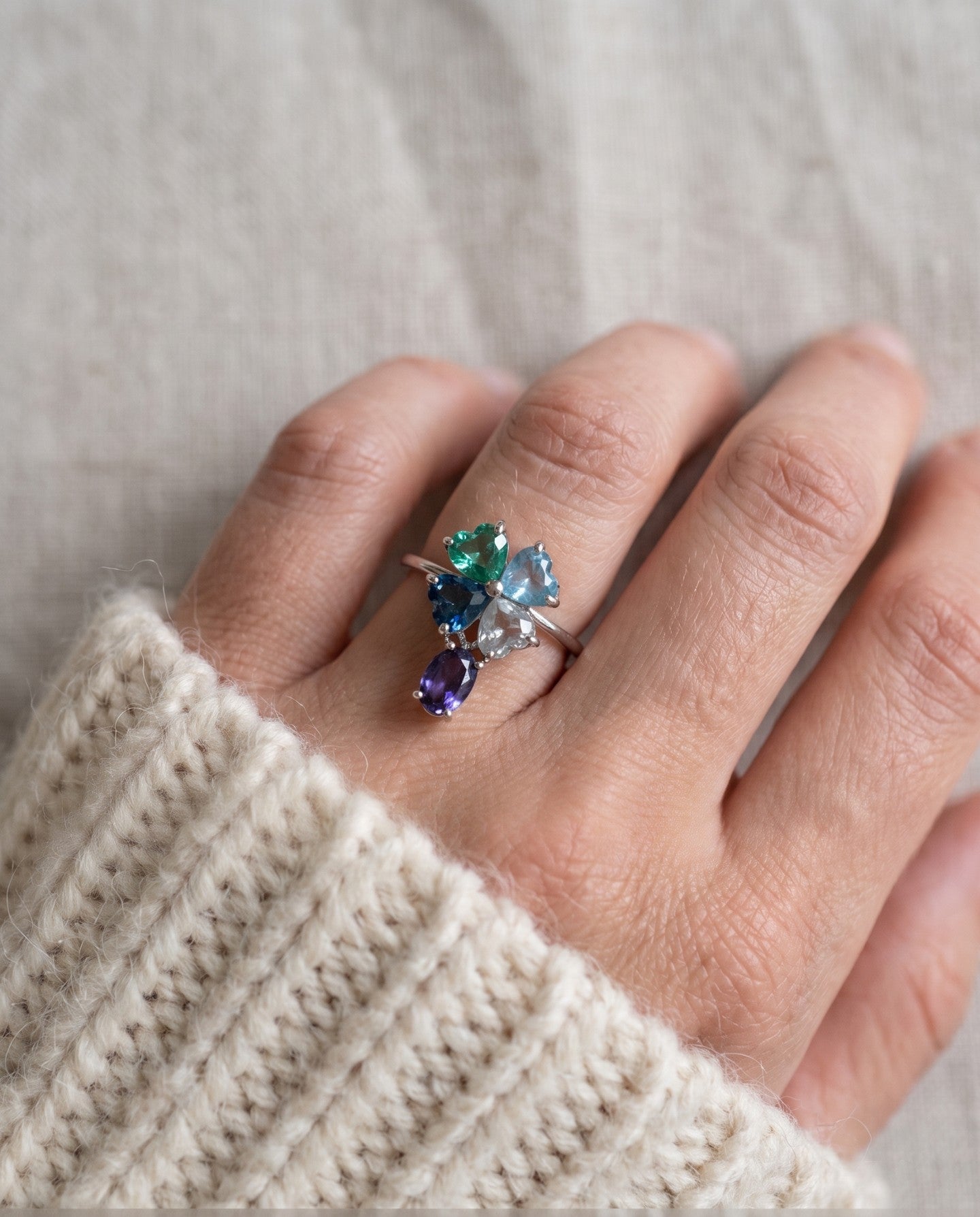 Silver blue topaz clover ring with dangling violet iolite worn on a hand