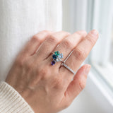 Silver blue topaz clover ring with dangling violet iolite worn with a slim stacking band