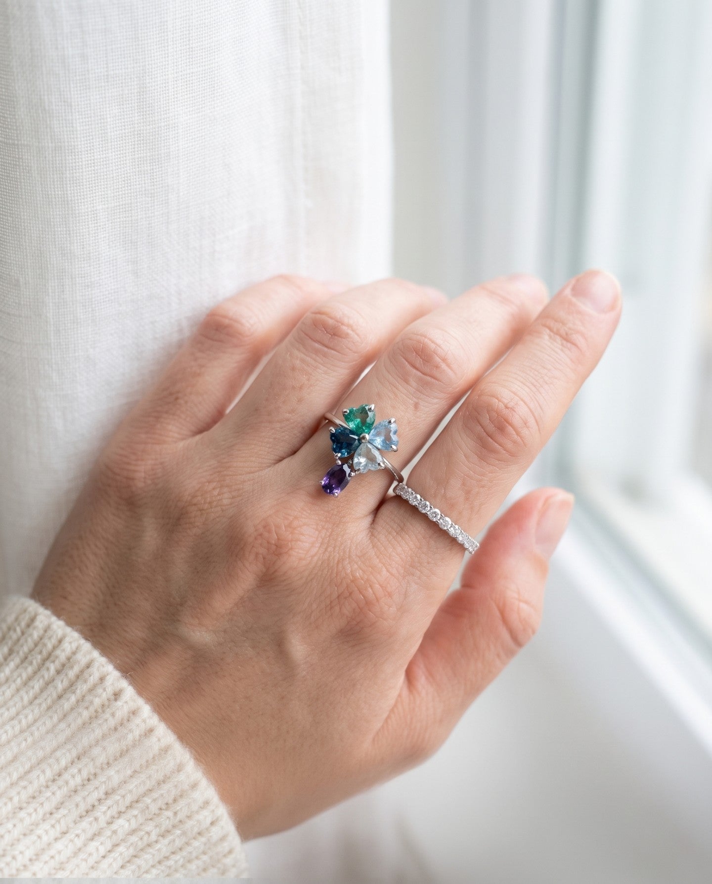 Silver blue topaz clover ring with dangling violet iolite worn with a slim stacking band