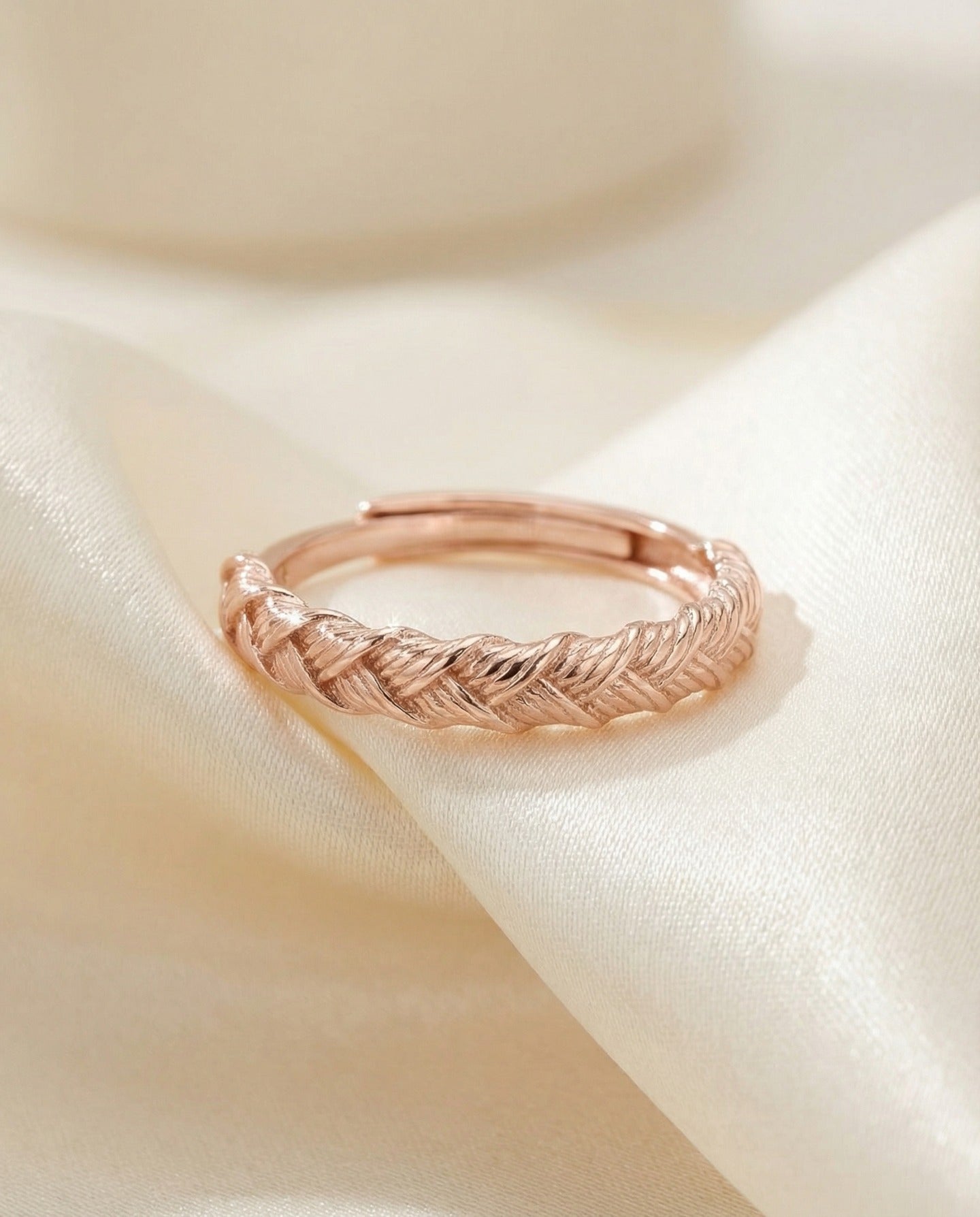 Braided Bliss Band in rose gold, braided band resting alone on ivory fabric