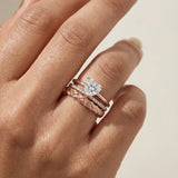 Braided Bliss Band in rose gold, worn beneath a solitaire ring in a close-up hand view