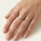 Braided Bliss Band in rose gold, styled on a hand beside a solitaire and a slim band