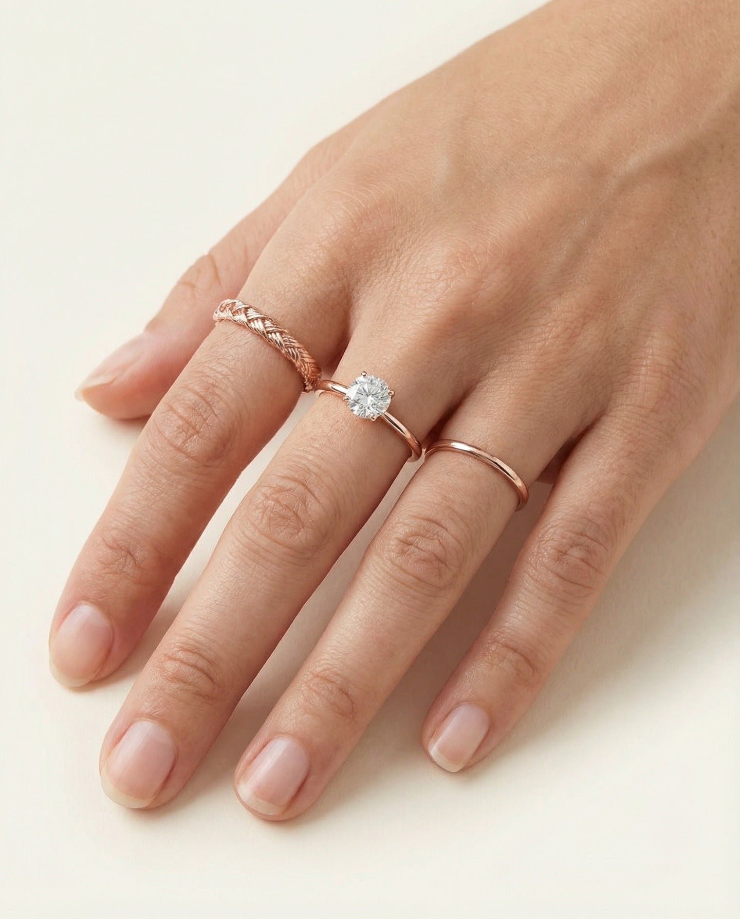 Braided Bliss Band in rose gold, styled on a hand beside a solitaire and a slim band