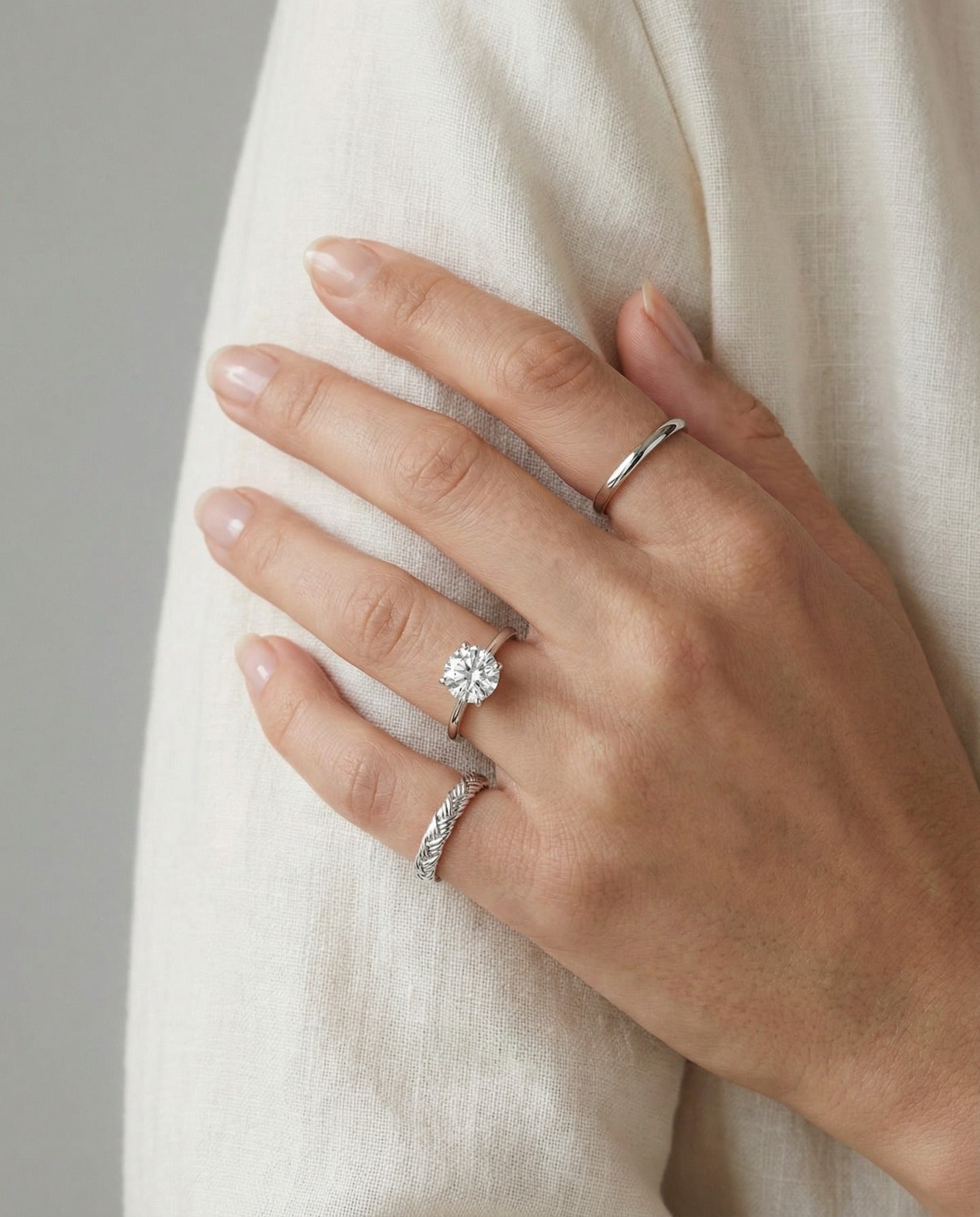 Braided Bliss Band in silver, worn on a hand against white fabric