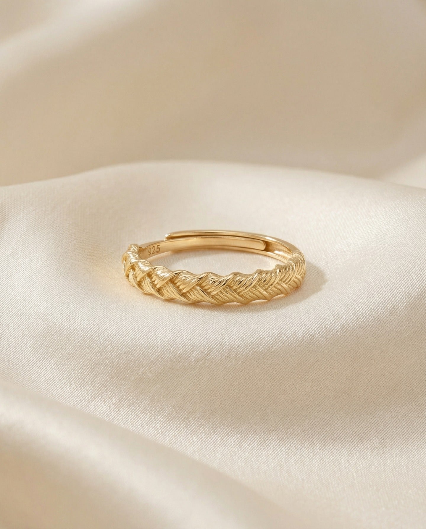 Braided Bliss Band in yellow gold, braided band displayed on folded cream fabric