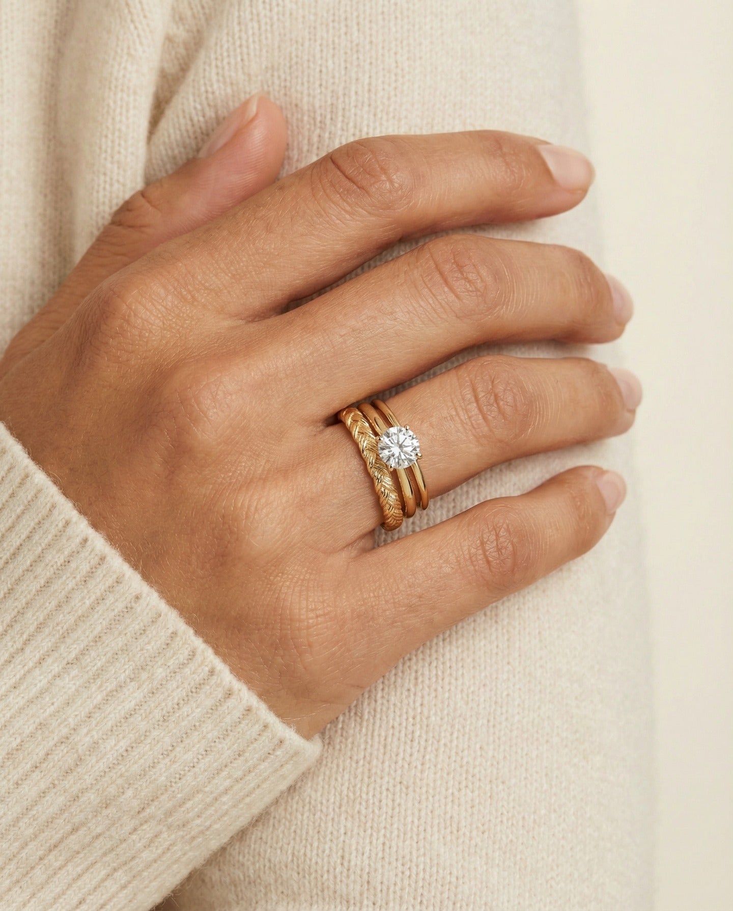 Braided Bliss Band in yellow gold, worn in a ring stack with an ivory knit sleeve