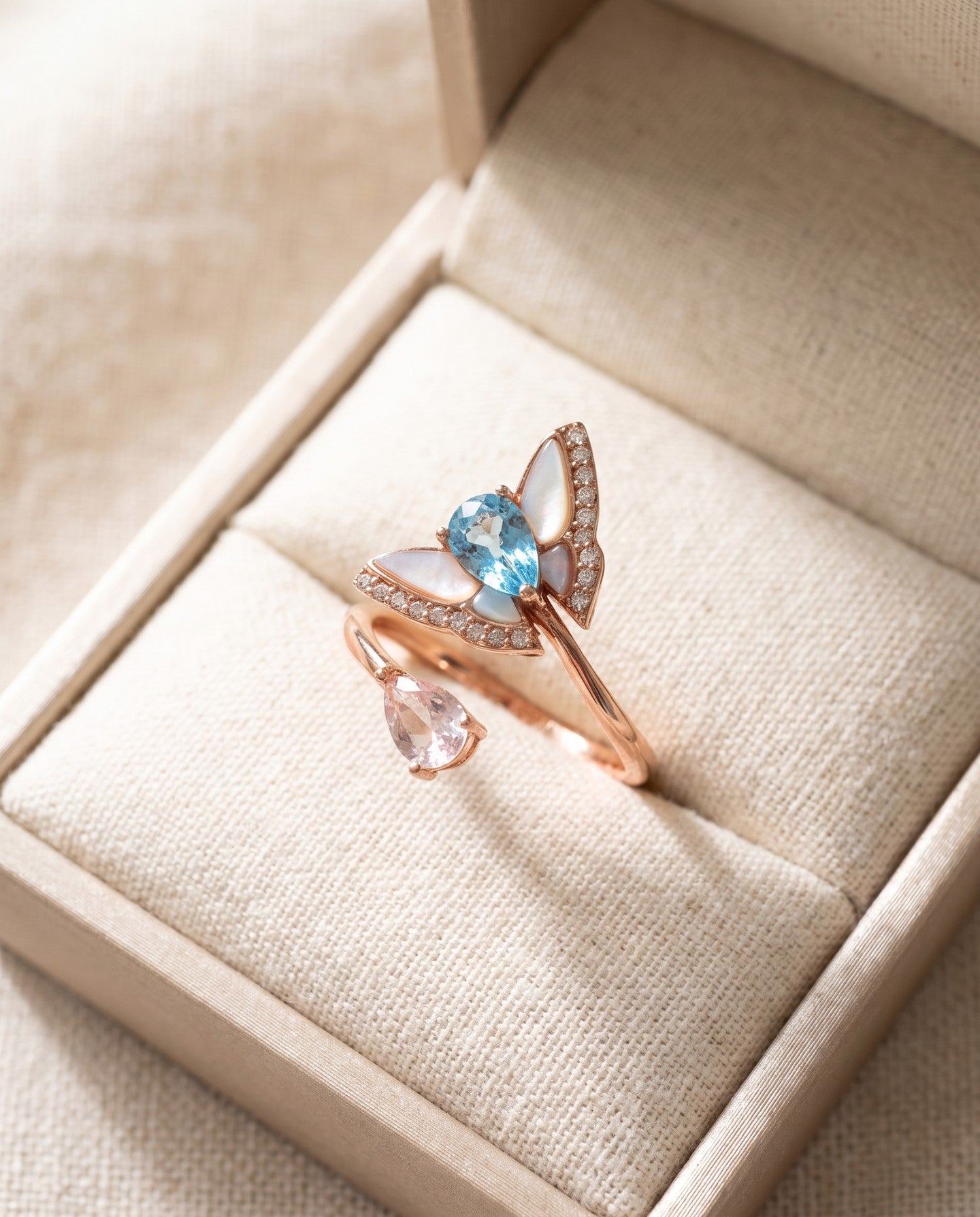 Rose gold butterfly ring with Swiss blue topaz, rose quartz and mother-of-pearl wings in an ivory jewellery box