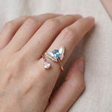 Rose gold butterfly ring with Swiss blue topaz and rose quartz worn on a hand