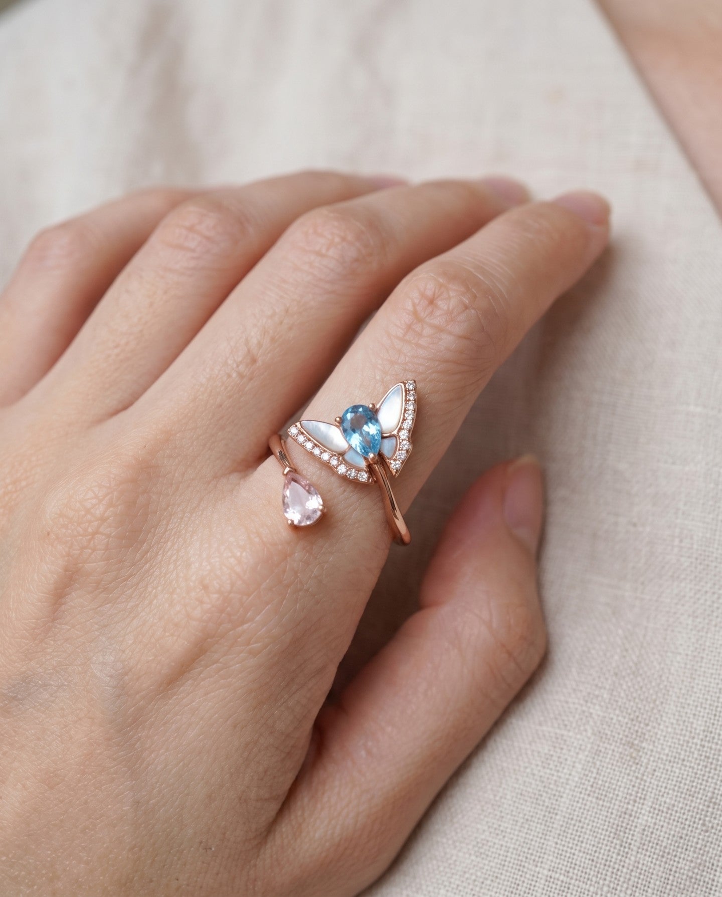 Rose gold butterfly ring with Swiss blue topaz and rose quartz worn on a hand
