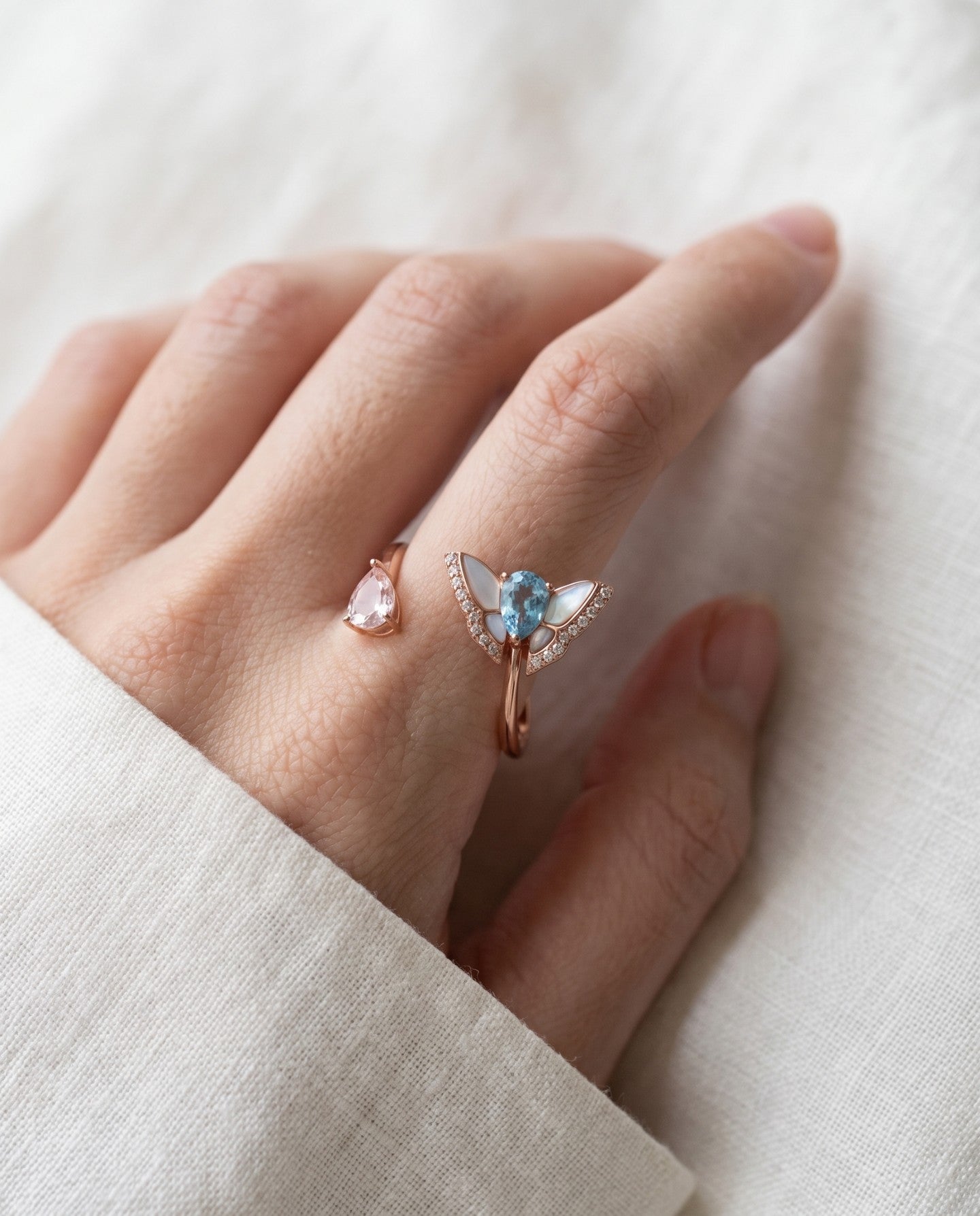 Rose gold butterfly ring with Swiss blue topaz and rose quartz worn on a hand