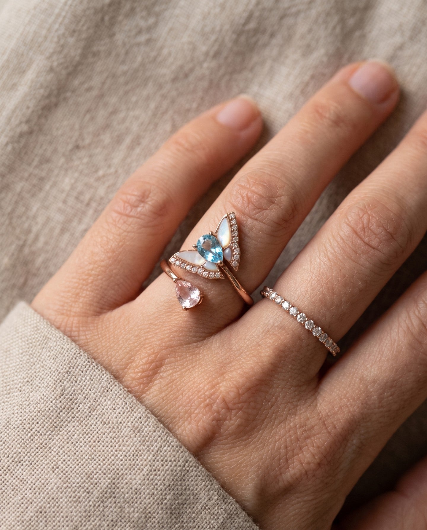 Rose gold butterfly ring with Swiss blue topaz and rose quartz worn alongside other rings
