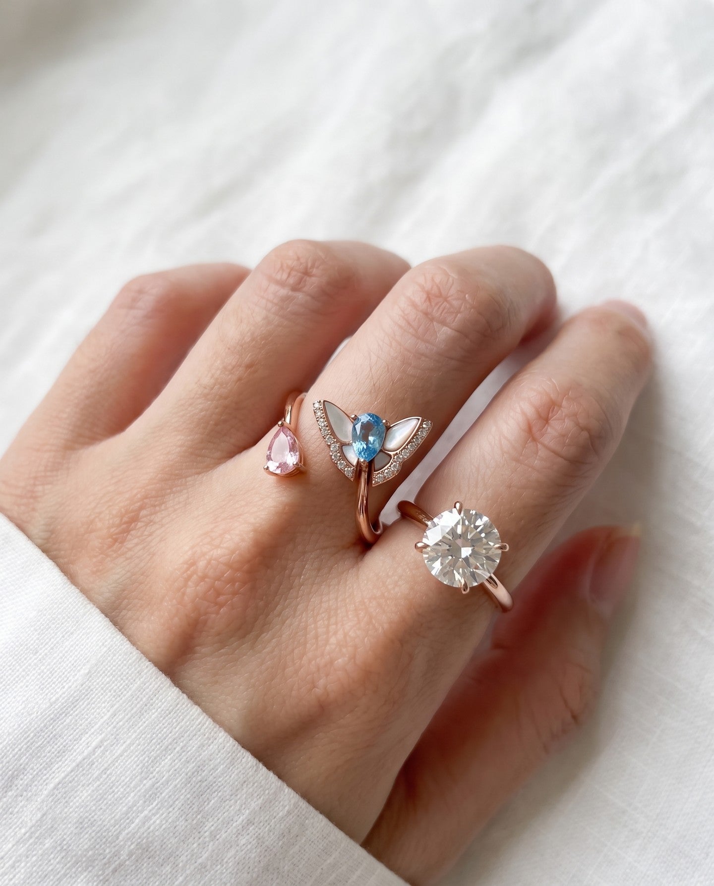 Rose gold butterfly ring with Swiss blue topaz and rose quartz worn alongside other rings