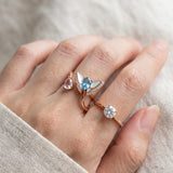 Rose gold butterfly ring with Swiss blue topaz and rose quartz worn alongside other rings