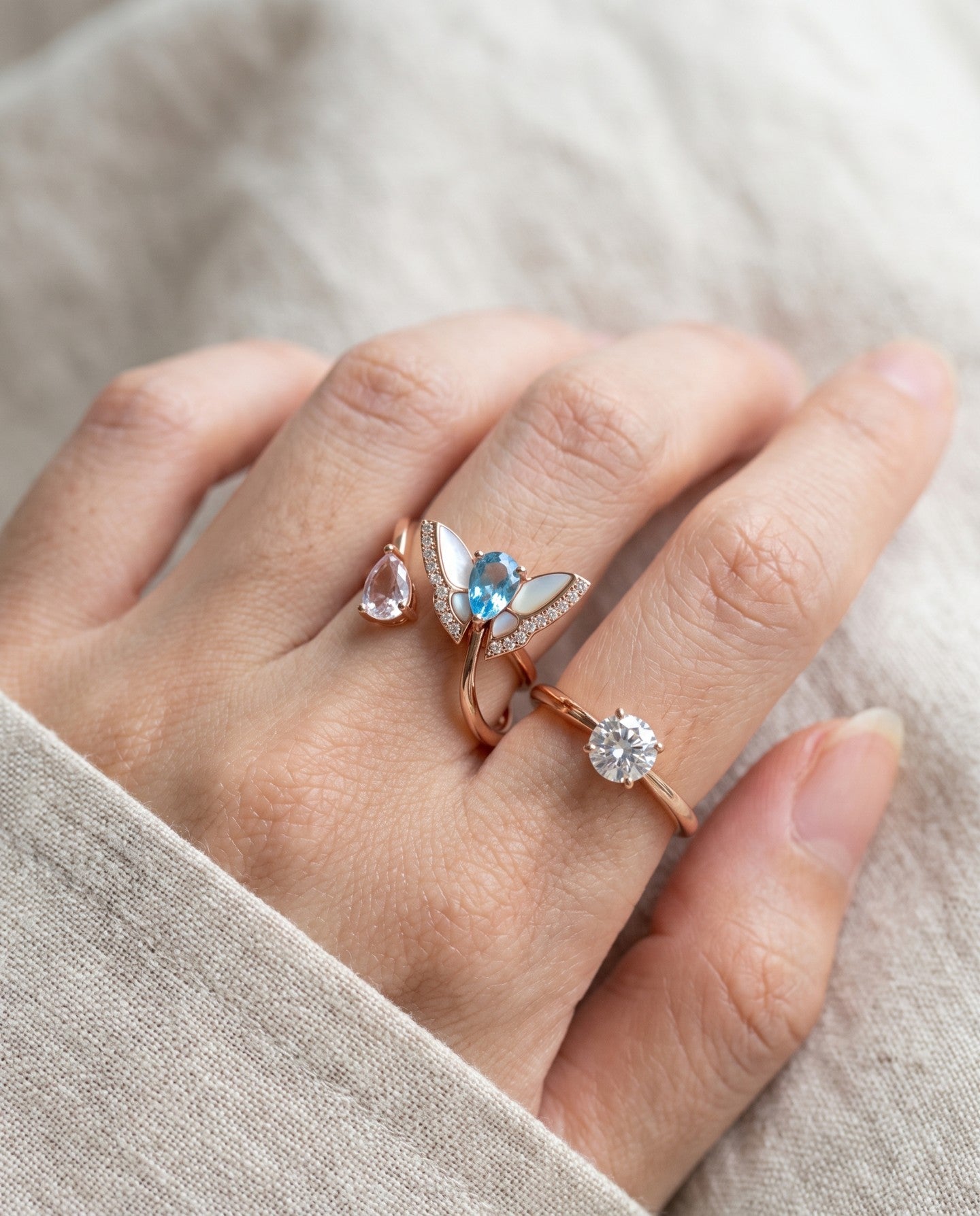 Rose gold butterfly ring with Swiss blue topaz and rose quartz worn alongside other rings