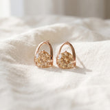 Champagne moissanite stud earrings in rose gold resting on ivory linen