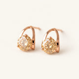 Champagne moissanite stud earrings in rose gold on an ivory background