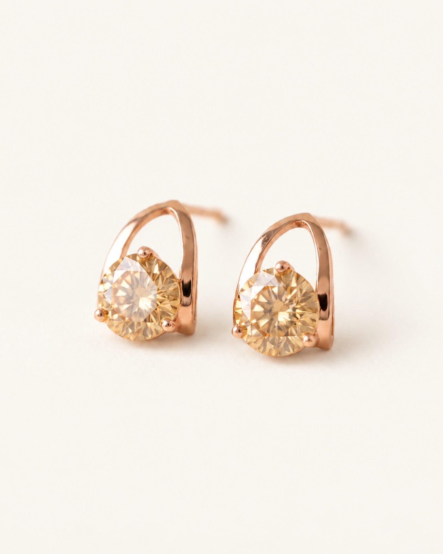 Champagne moissanite stud earrings in rose gold on an ivory background