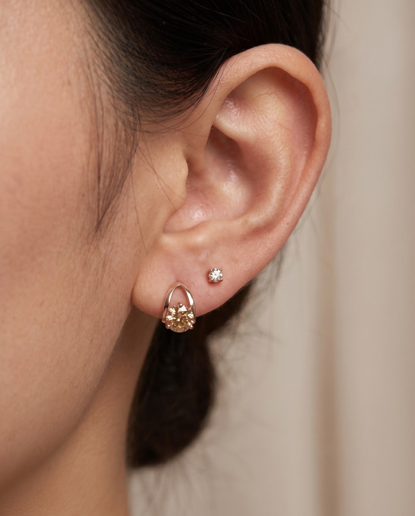 Champagne moissanite stud earrings in rose gold worn on an ear