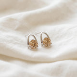 Champagne moissanite stud earrings in silver resting on ivory linen