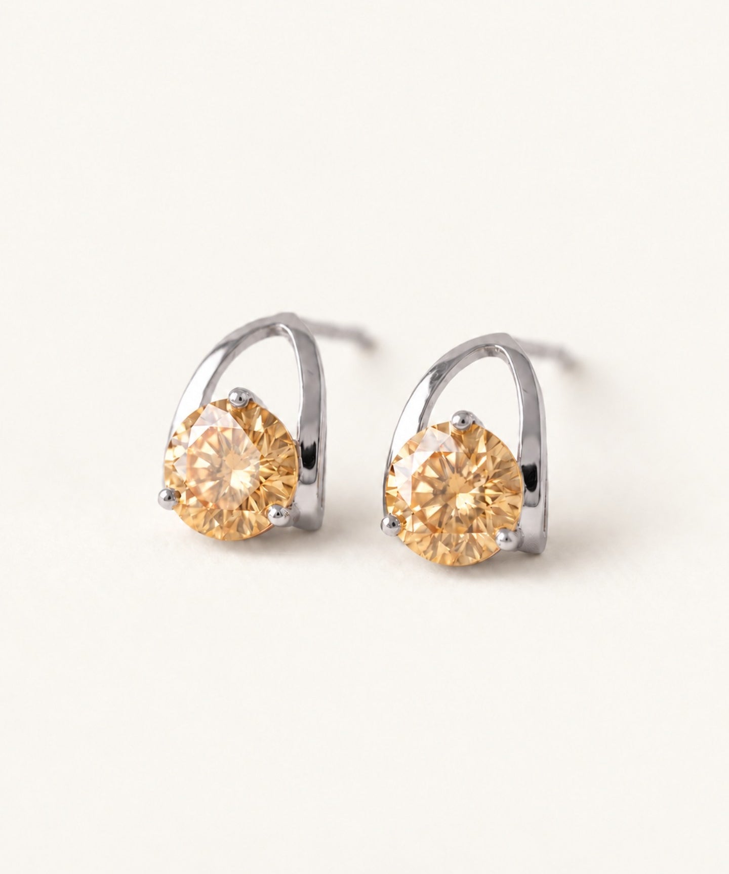 Champagne moissanite stud earrings in silver on an ivory background